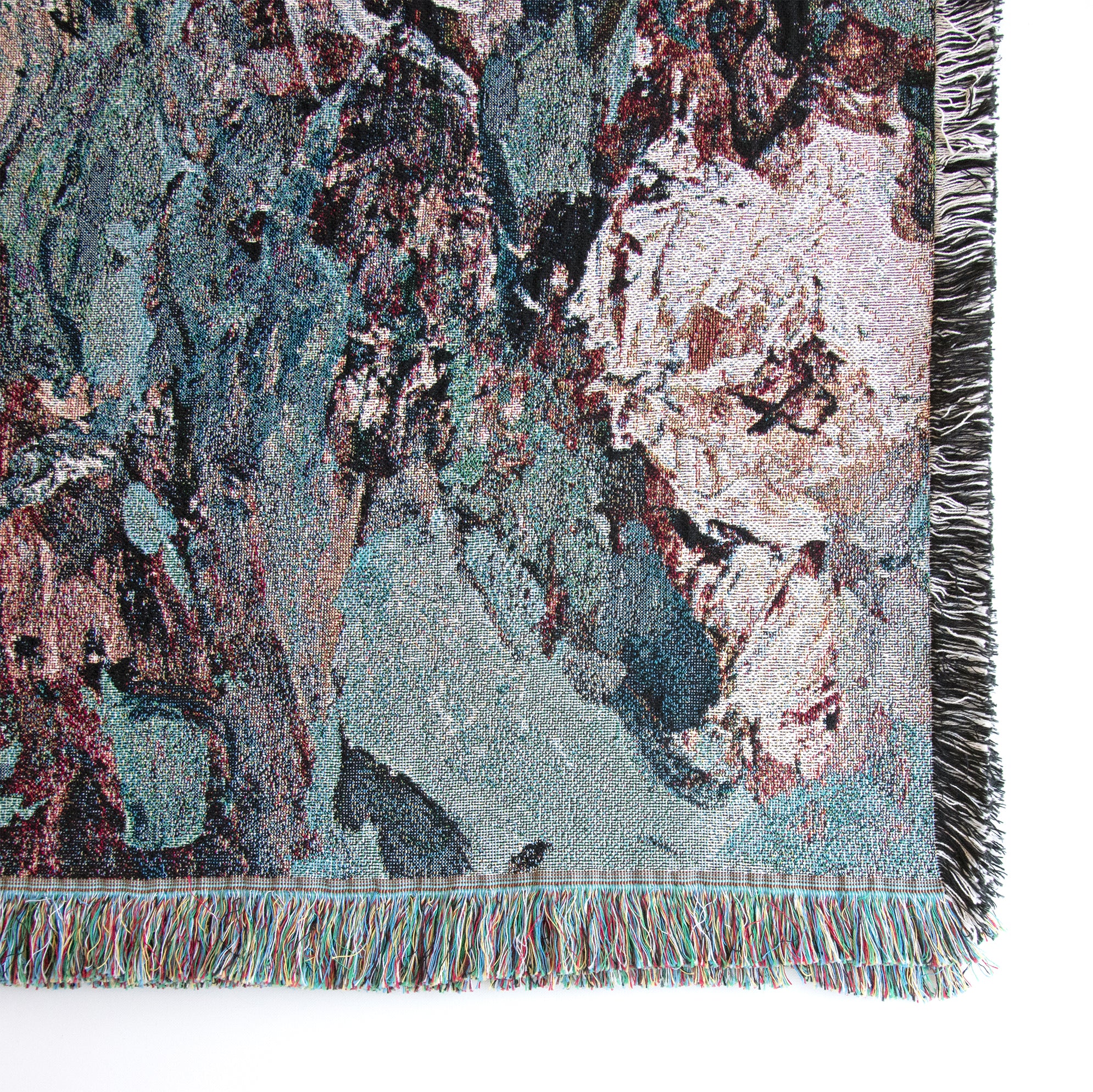Close-up of lower right corner of woven blanket showing details of roses, the weave, and fringed edges. 