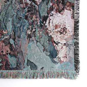 Close-up of lower right corner of woven blanket showing details of roses, the weave, and fringed edges. 