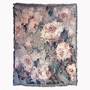 Floral patterned decorative woven blanket with impressionist design of roses, showing a soft texture and fringed edges, on a white square background. 