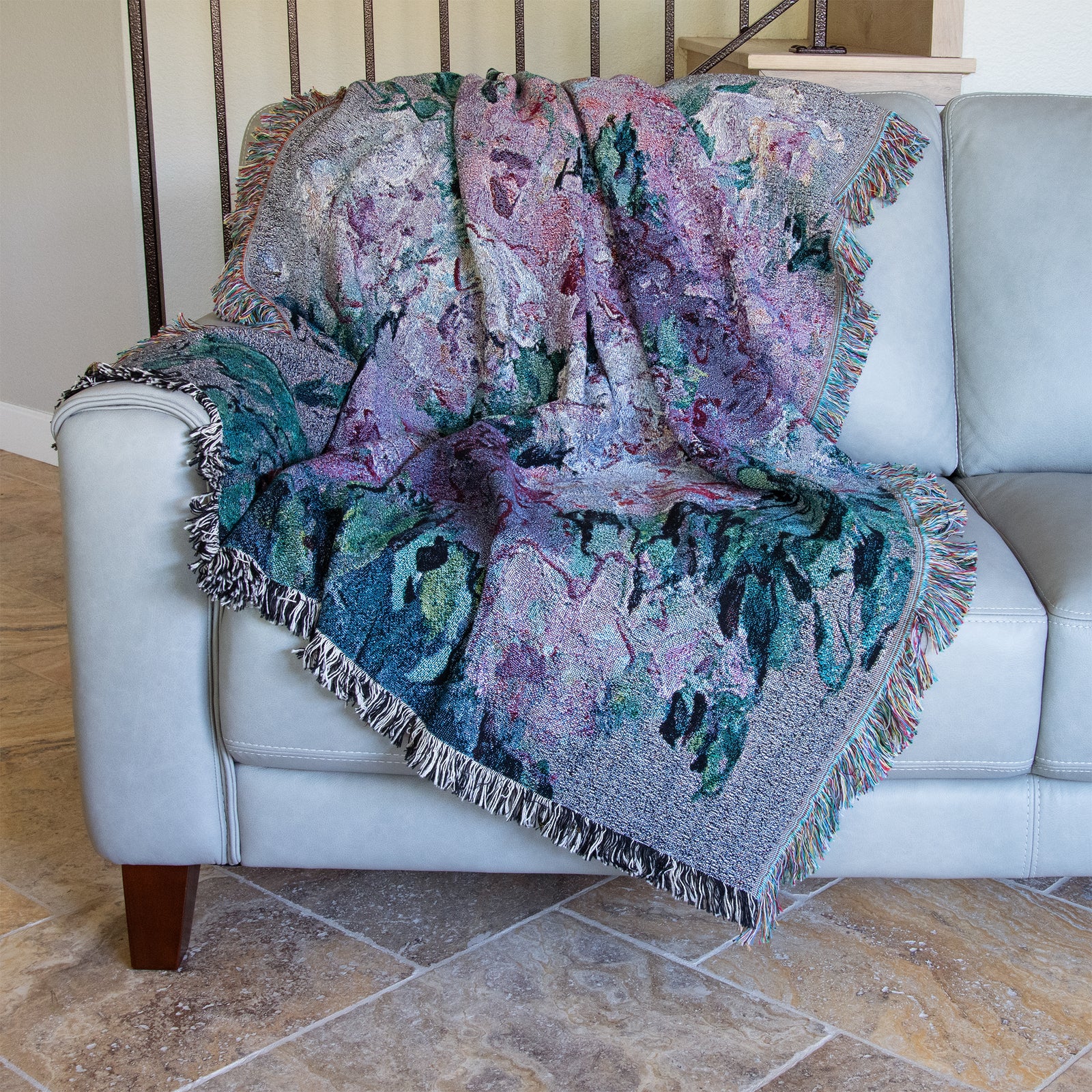 Fine art woven blanket with pink and violet rose blossoms and deep green leaves in an impressionist style, with effect of a tapestry, with fringed edges. 