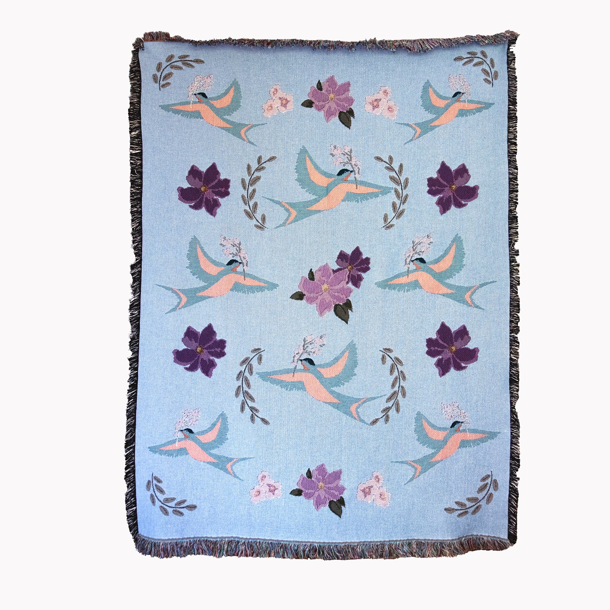 Decorative fine art blanket with blue birds and flower pattern woven into a light blue background, with fringed edges.